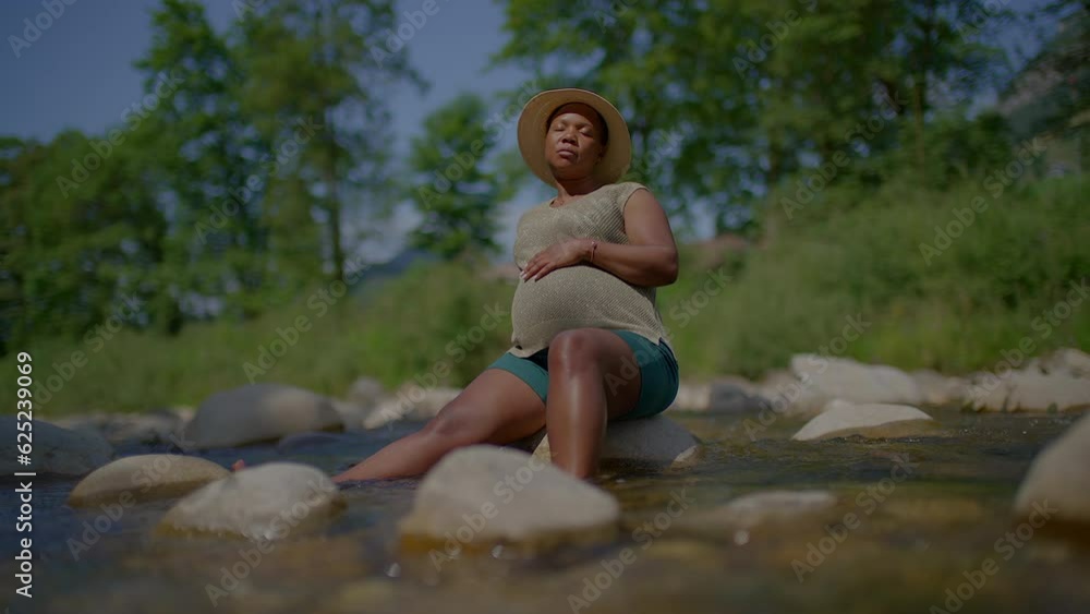 Young Pregnant African Woman Enjoying Nature Outdoors Relaxing in Peaceful River Water Young Pregnant African Woman Enjoying Nature Outdoors Relaxing in Peaceful River Water