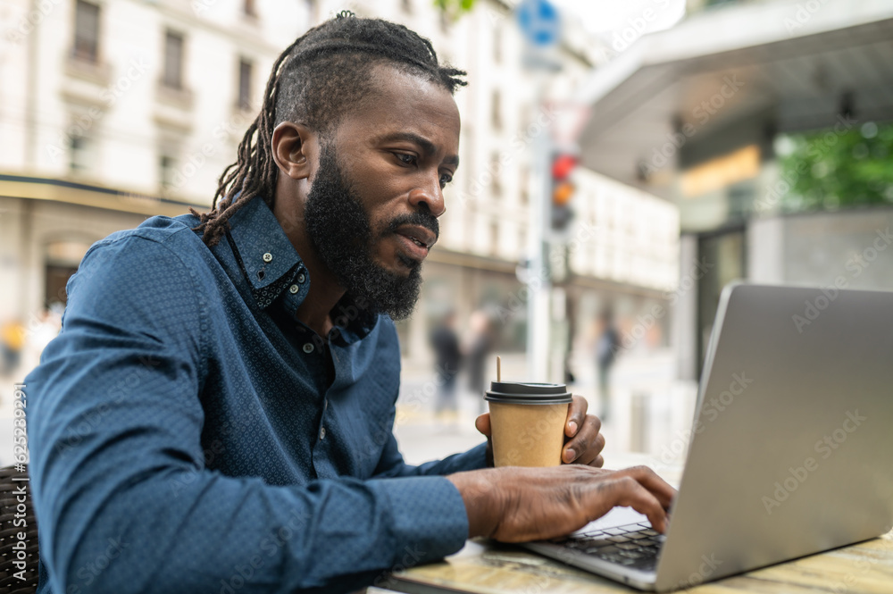 Dark-skinned young man working in a cafe outdoors