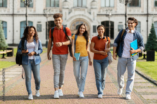 Group of cheerful college students walking out of campus together