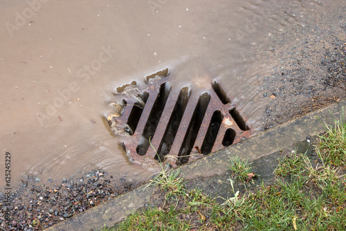 Rainwater flowing down road drain, UK