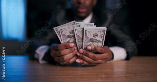 Close up shot selective focua African American brilliant mathematician or codebreaker, using the dollars as a cryptic message or puzzle to solve, leading him to a hidden secret or treasure. photo