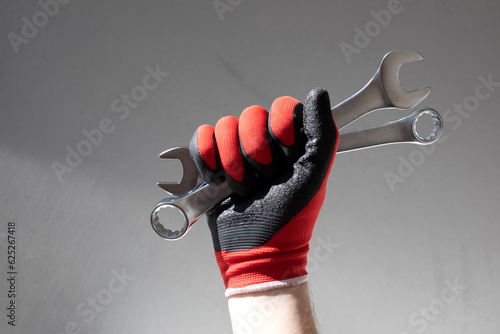 Working tools for repair. Man in denim holding grey wrenches in his hands. Front view