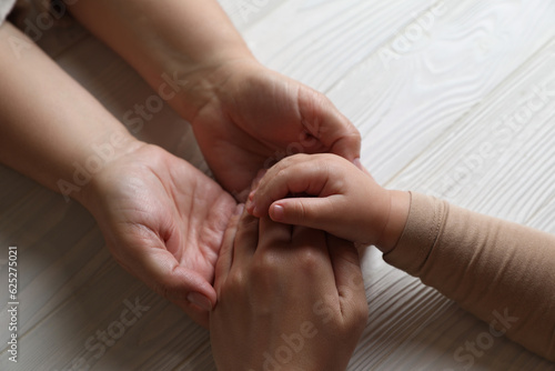 Family holding hands together at white wooden table, above view