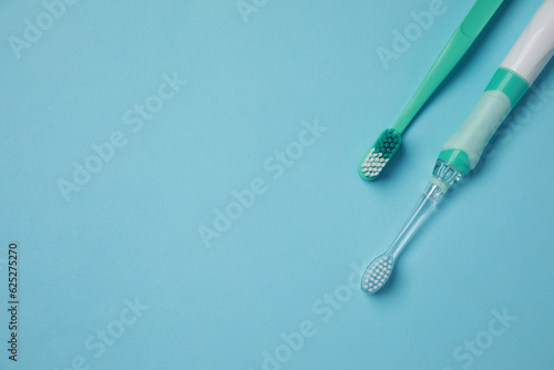 Electric and plastic toothbrushes on turquoise background, flat lay. Space for text