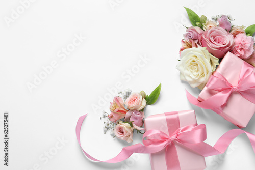 Gift boxes and beautiful flowers on white background, flat lay. Space for text