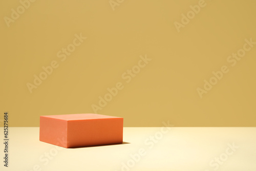 Orange stand on table against yellow background, space for text. Stylish presentation for product