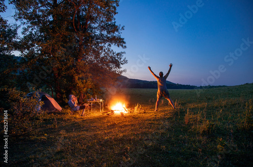 Two tourists rest in nature in the evening by the fire