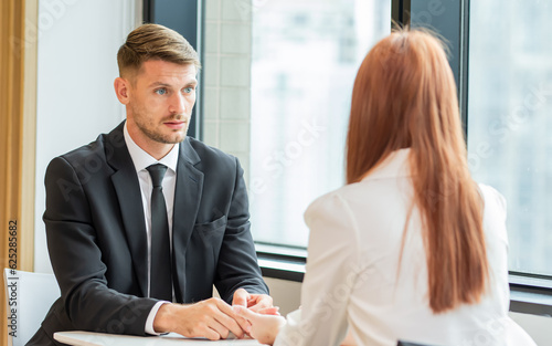 Schilderij op canvas Selective focus caucasian white smart business man wearing formal suit with necktie, seriously talking and discussing with staff, sitting beside window in indoor office