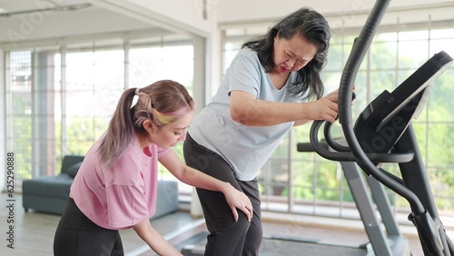 Asian elderly women suffering pain from exercising on the machine and young daughter rushed to take care. Young women take care knee pain of her mother while exercising. Pain from exercise