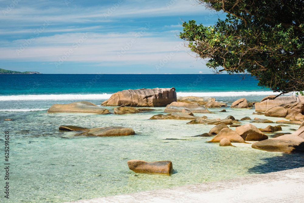 Big granite rocks on the Grand Anse beach. La Digue island, Seychelles. Tropical landscape with sunny sky.