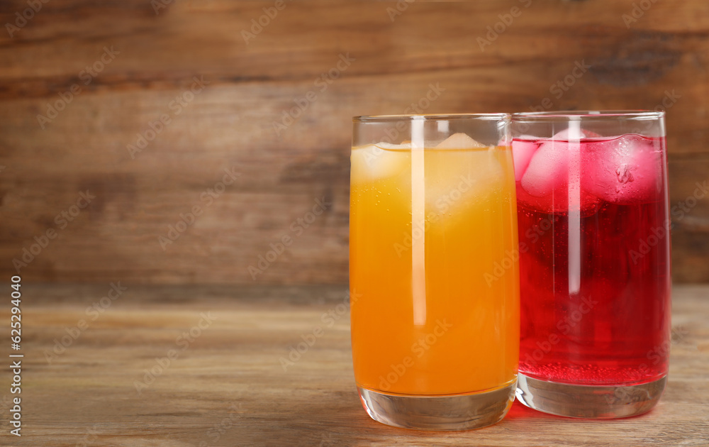 Glasses of different refreshing soda water with ice cubes on wooden table. Space for text Glasses of different refreshing soda water with ice cubes on wooden table. Space for text