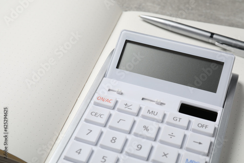 Calculator and pen on open notebook, closeup