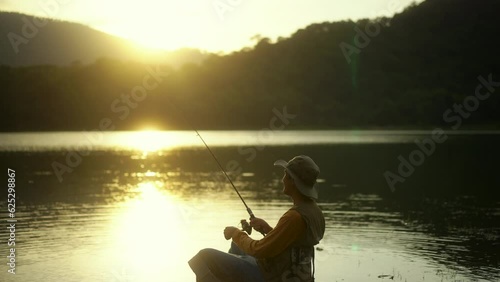 Wallpaper Mural 
Handsome man fishing as a leisure activity during his vacation and sitting in the lake on sunset. Relax and hobby concept. Torontodigital.ca