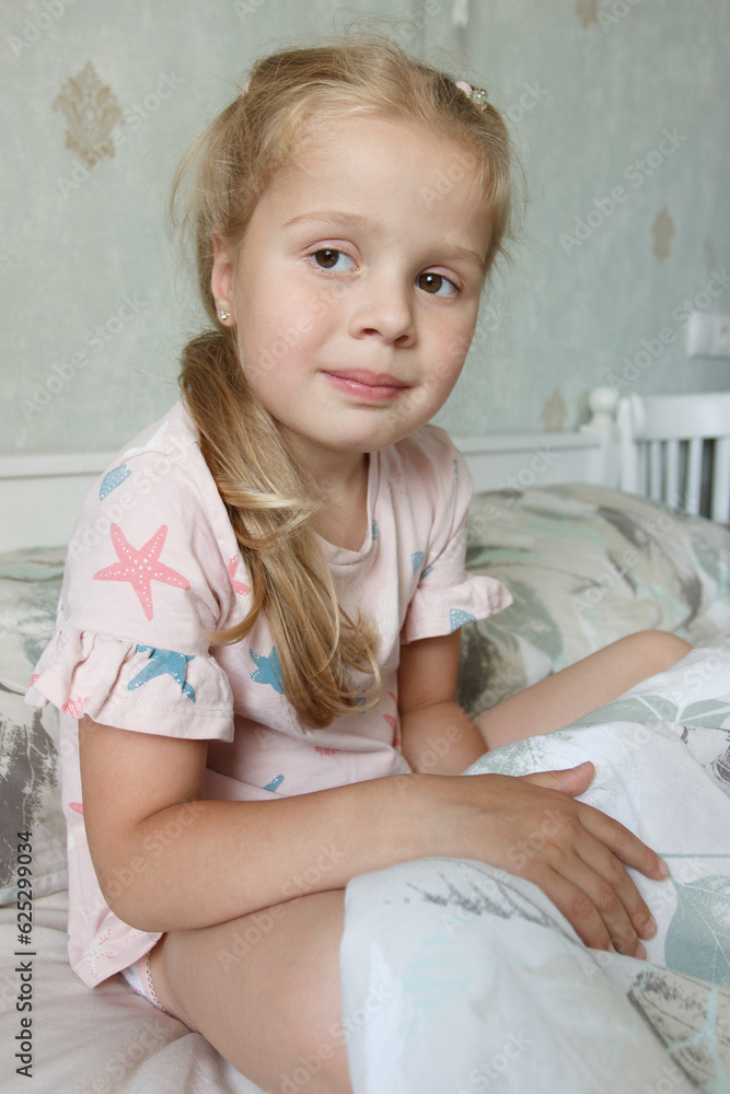Cute little girl sitting on the bed and smiling. Concept of a leisure Cute little girl sitting on the bed and smiling. Concept of a leisure