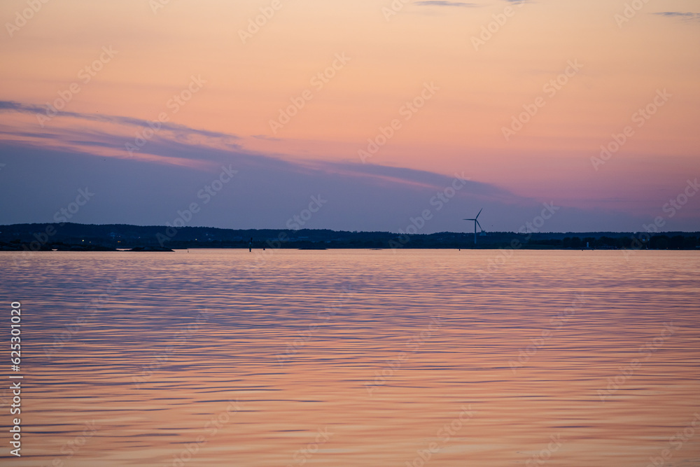Evening light over a wind turbine by the sea.
