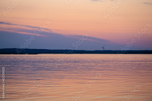 Evening light over a wind turbine by the sea.