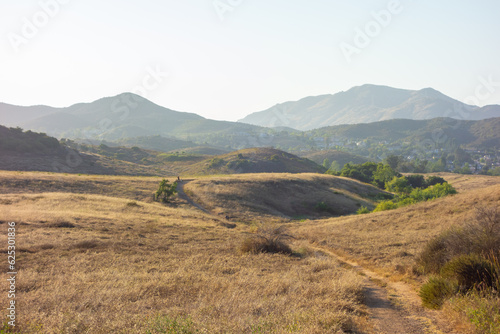 Hiking Views of golden grass, green bushes, and the Santa Monica Mountians, in Ventura County during the summer.