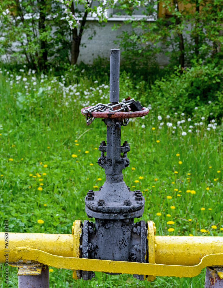 Gas shut-off valve at gas processing station locked with a metal chain and the lock . Valve on the gas boiler house.