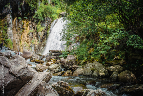 Korbu Waterfall is located on one of shores of Lake Teletskoye, Altai Republic, Siberia, Russia. Spring landscape, beautiful waterfall surrounded by trees and rocks, tourism place, nature environment