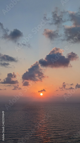 Sunrise over sea, view from beach to open sea and horizon, new day dawning.