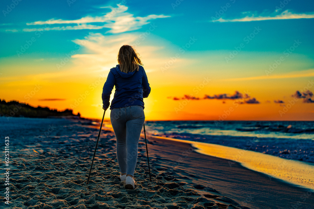 Nordic walking - woman training on beach at sunset
