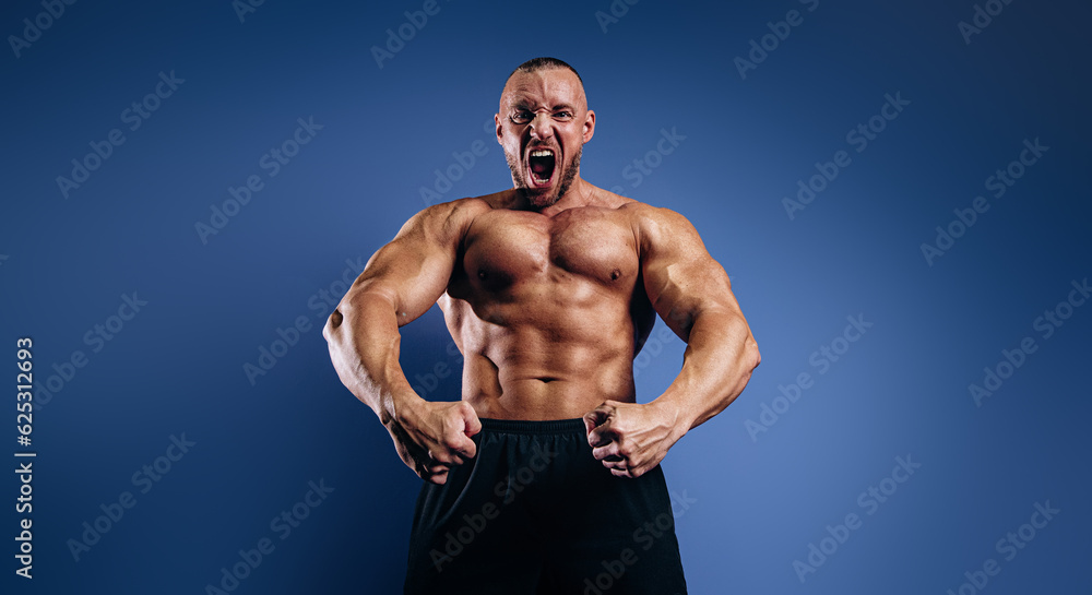 Emotional bodybuilder screaming and showing muscles on blue background. Fit man with muscular body