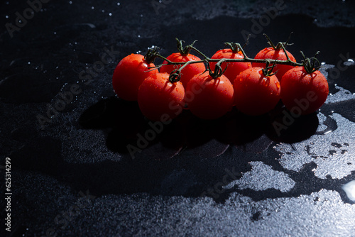 fresh tomatoes on black background with water drops