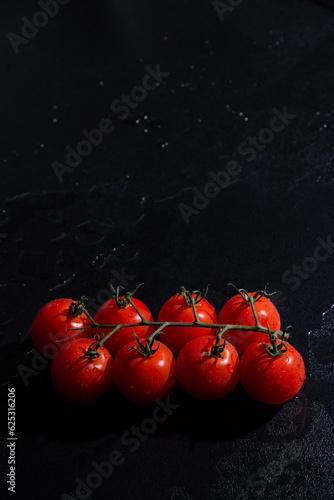 fresh tomatoes on black background with water drops