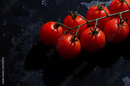 fresh tomatoes on black background with water drops
