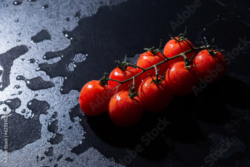 fresh tomatoes on black background with water drops