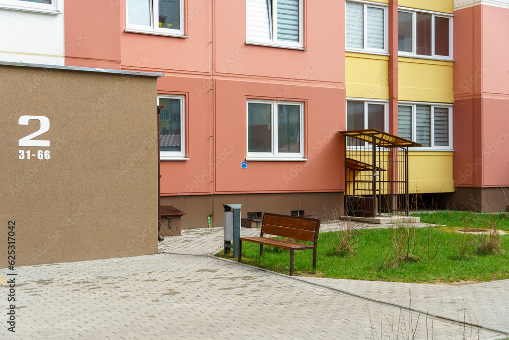 Fototapeta premium Well-groomed and clean courtyard of a multi-storey building. View of the entrance and the first floor of a residential building. Developed and safe for recreation infrastructure