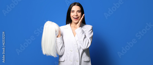 Excited young woman with wig on blue background