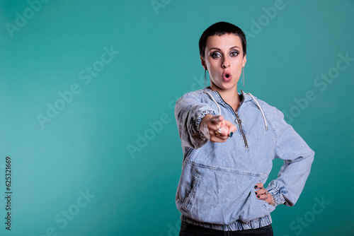 Displeased sad woman pointing index finger in front of camera screaming during studio shot on isolated background. Upset nervous female having mental breakdown, disappointment expression