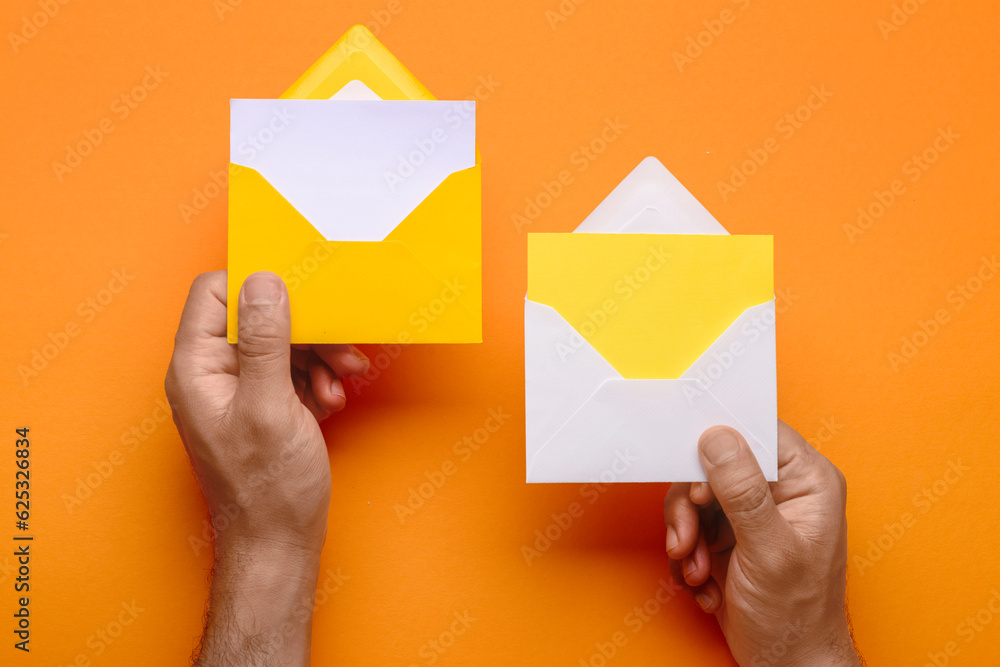 Male hands with envelopes and blank cards on color background, closeup