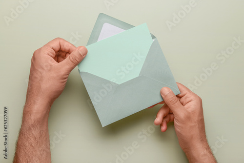 Male hands with envelope and blank card on color background, closeup