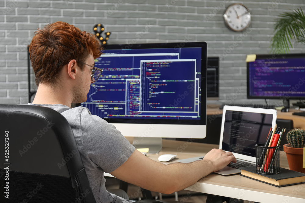 Male programmer working with laptop at table in office Male programmer working with laptop at table in office
