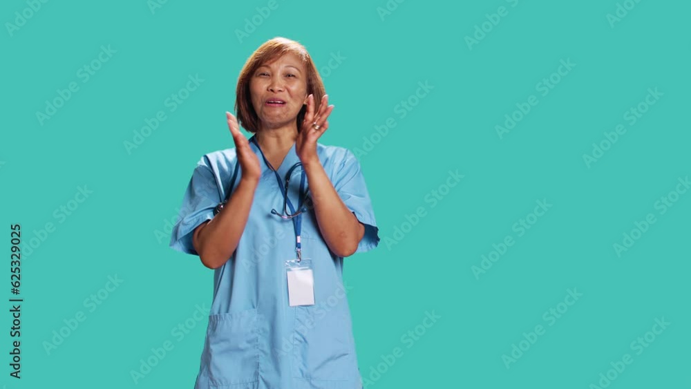 Approving smiling nurse happily clapping hands, satisfied with accomplishments. Healthcare specialist cheering, doing praising gesture while at work, isolated over blue studio background Approving smiling nurse happily clapping hands, satisfied with accomplishments. Healthcare specialist cheering, doing praising gesture while at work, isolated over blue studio background