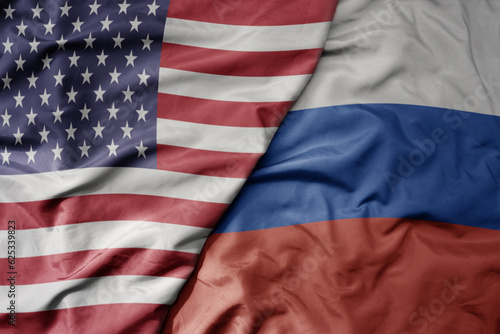 big waving colorful flag of united states of america and national flag of russia .