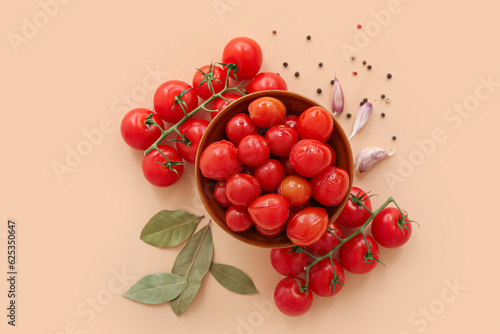 Bowl with canned tomatoes and garlic on beige background