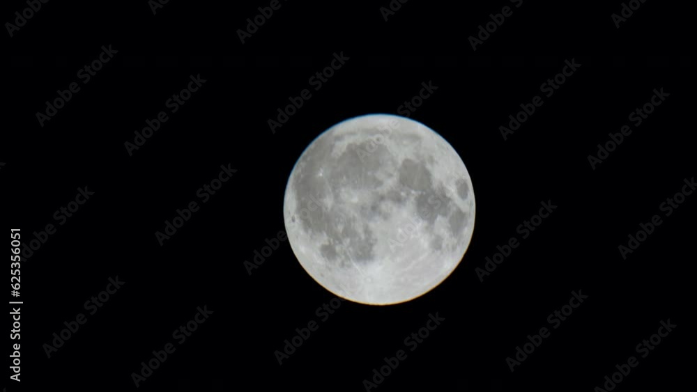 Big full moon sets in the night sky. Moon gradually descends in the black sky. A beautiful moonlight night an impending storm in a starless dark sky. Closeup. Moon hiding behind the houses. 4k footage Big full moon sets in the night sky. Moon gradually descends in the black sky. A beautiful moonlight night an impending storm in a starless dark sky. Closeup. Moon hiding behind the houses. 4k footage