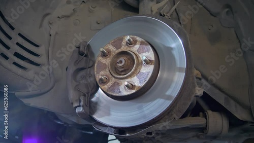 Car Wheel Hub With Brake Disc, inspect brake disc with caliper on the car, bottom view. Repairing a brake disc in a car repair shop. Old rusty brake disc close-up. Rusty hub of a car wheel photo