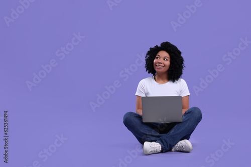 Happy young woman using laptop on purple background. Space for text