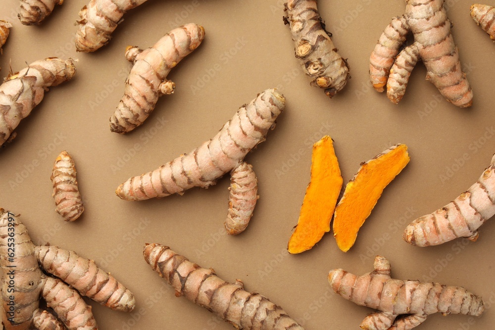 Many raw turmeric roots on light brown table, flat lay Many raw turmeric roots on light brown table, flat lay