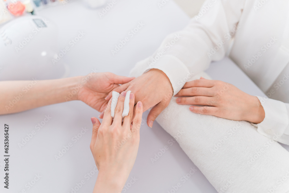 Fototapeta premium ネイルサロンでアセトンでネイルオフをするネイリストとアジア人女性 