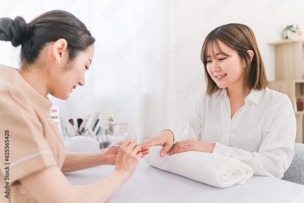 ネイルサロンでプッシャーを使って甘皮ケアをするネイリストと女性
ネイルサロンでプッシャーを使って甘皮ケアをするネイリストと女性