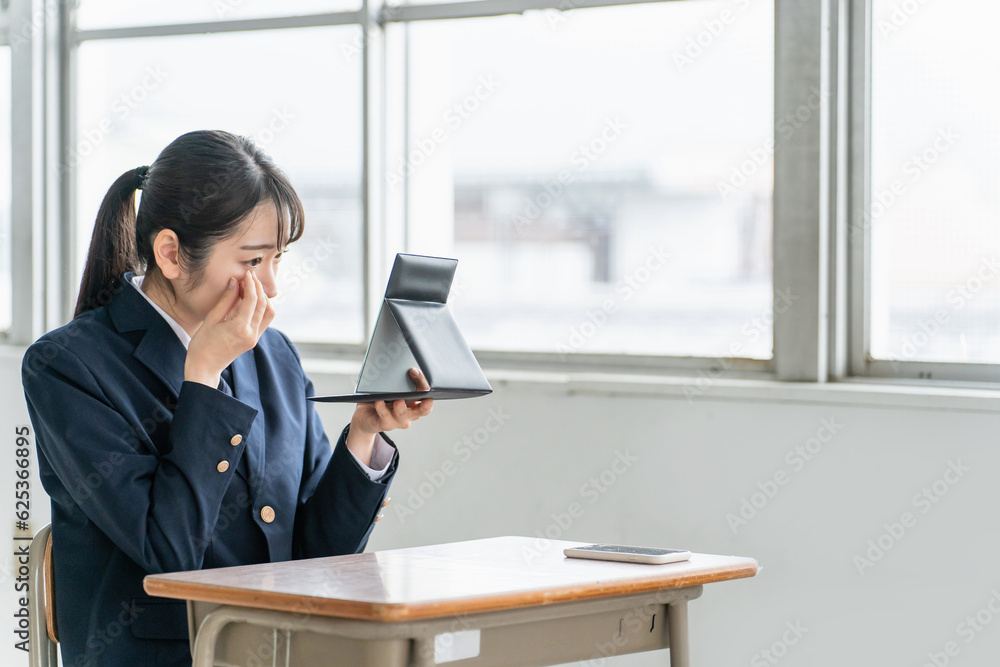 教室で鏡を見ながらコンタクト・カラコンを入れる女子高生
