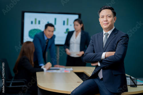 Handsome Asian middle-aged executives business man standing confident in the office in front of his team.