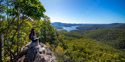 hiker girl admiring the panorama of advancetown lake and springbrook national park as seen from the top of pages pinnacle mountain ridge; hiking in the mountains near gold coast, queensland, australia