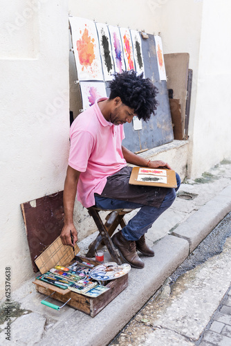 Photography african american man artist or painter in the street painting on footpath in Lat