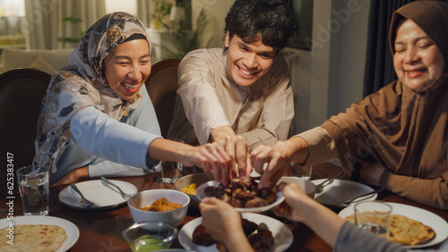 Eid Mubarak Muslim Asia family have Iftar dinner eat dates fruit to break feast. Eat traditional food during Ramadan fasting month at home, The Islamic Halal Eating and Drinking at modern Islam.